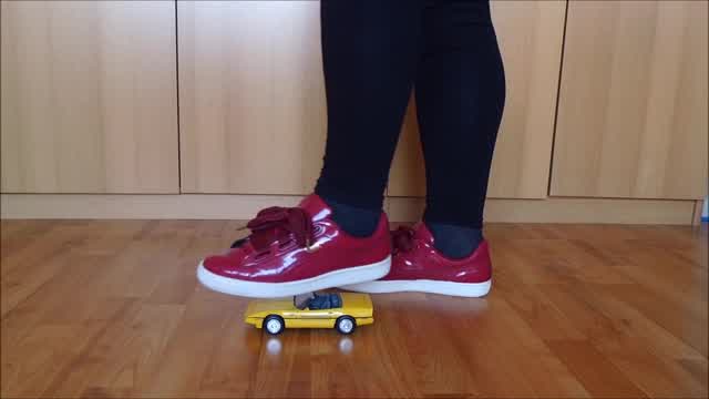 Jana crushes a model car with her red patent Puma Basket sneakers trailer